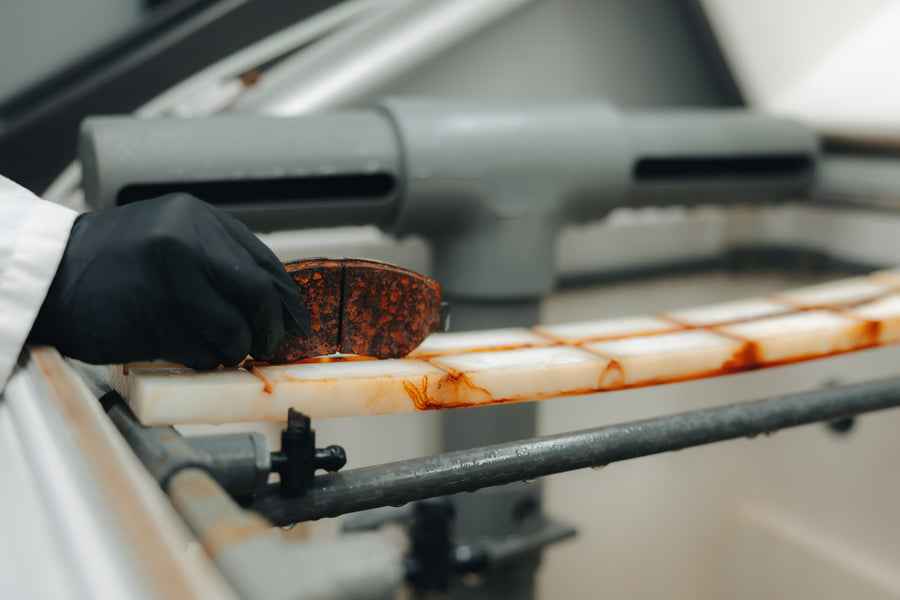 A gloved hand holding a backing plate after corrosion testing